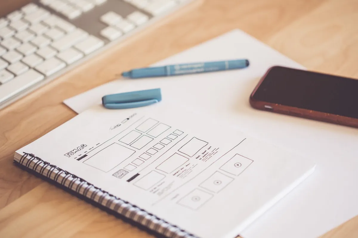 Mobile and website wireframes beside a smartphone and keyboard